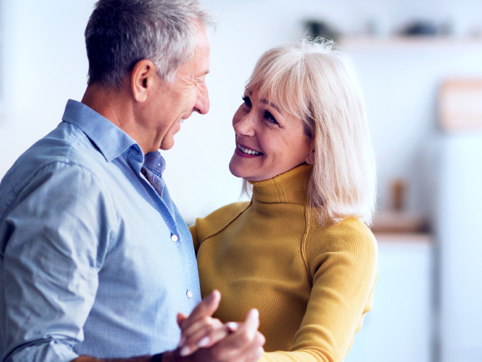 Ein älteres Paar tanzt in seinem Zuhause und hält sich an den Händen