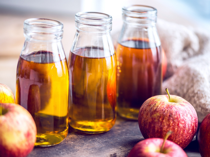Nahaufnahme von drei Glasflaschen mit frischem Apfelessig zur Verdauungsanregung