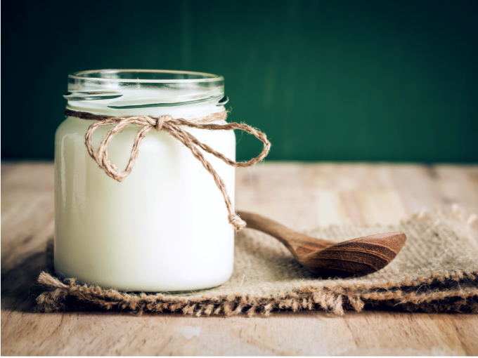 Schraubglas mit Joghurt steht auf einem Holztisch