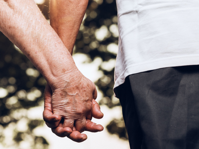 Nahaufnahme zweier älterer Menschen, die sich an den Händen halten